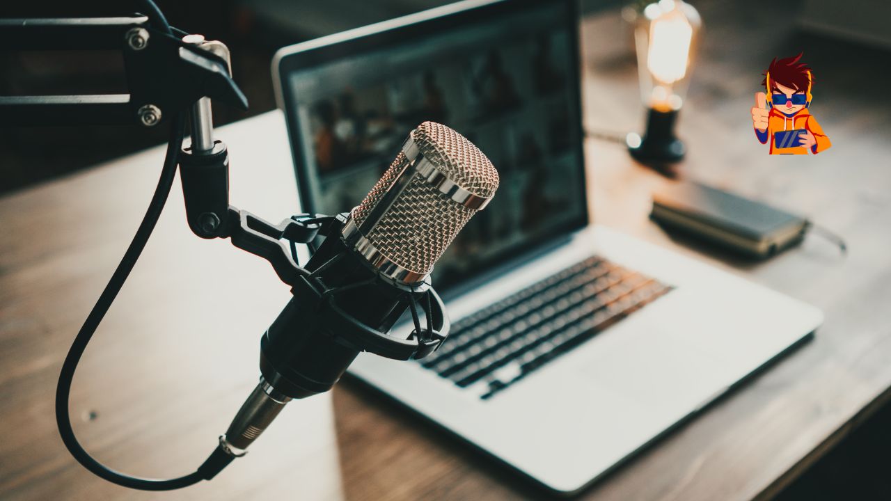 Close-up of a podcast microphone in front of an open laptop on a wooden desk, with a warm ambient light in the background.